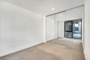 An empty room with the windows' reflection in the mirrored closet